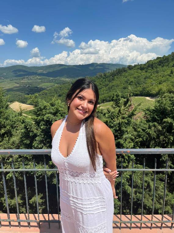 Camryn Traylor poses on a balcony overlooking a picturesque landscape.