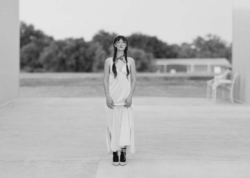 Black and white photo of Tierani Bryan posing on a concrete platform in a field
