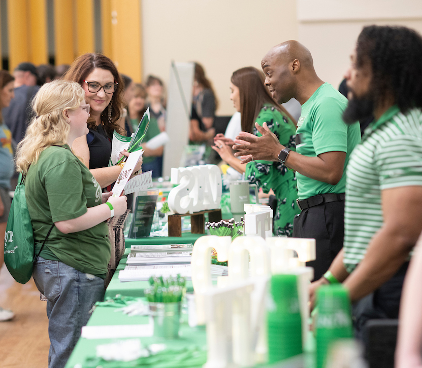 A parent and student chat with a tabling representative at Fall Preview 
