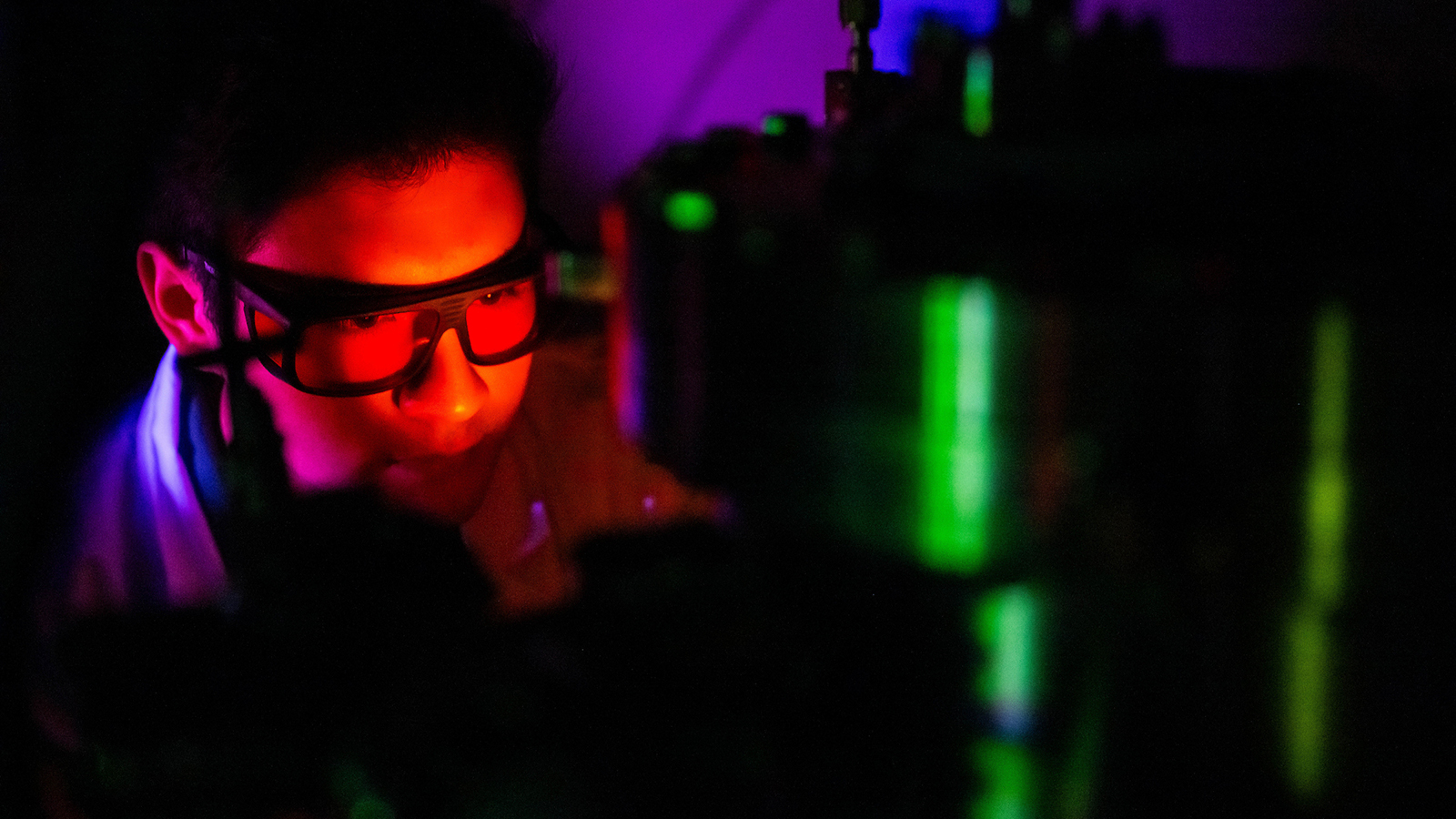 A colorfully-lit student works in a semiconductor manufacturing lab