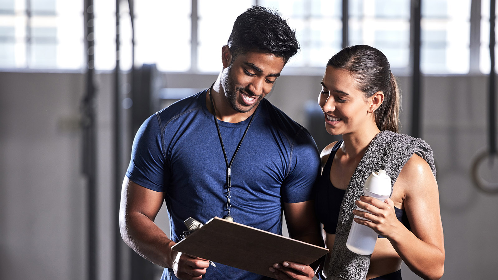 Two people discussing an item on a clipboard in a gym