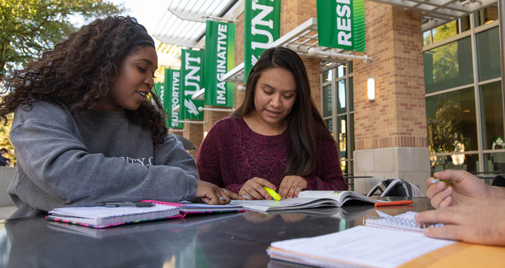 Estudiante estudiando afuera con su amiga