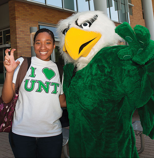 Student posing with UNT mascot Scrappy