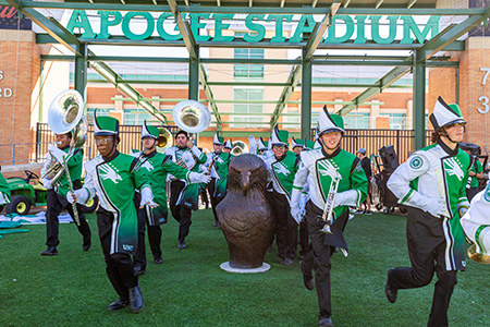 Machring band entering under Apogee Stadium Arch