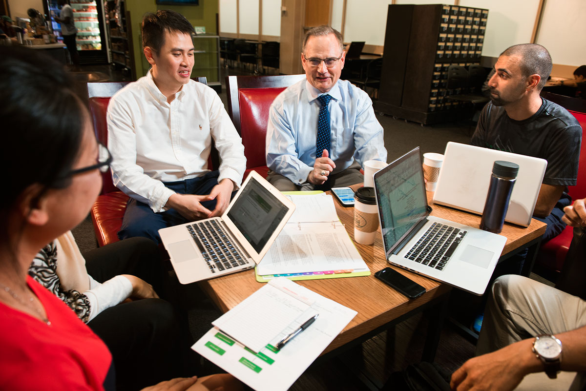 People sitting around a table with laptops