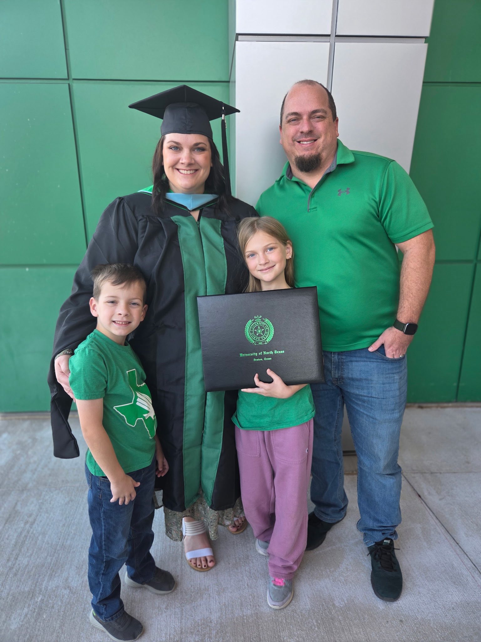 Abigail poses in a green commencement gown