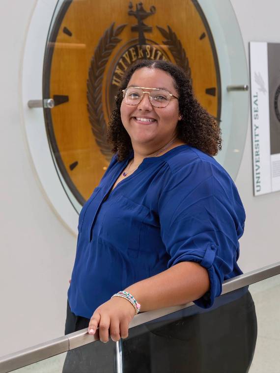 Photo of Jacklyn Perez posing in front of UNT's university seal