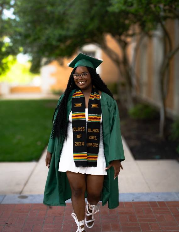 Jermiah Crowder poses outdoors in commencement regalia