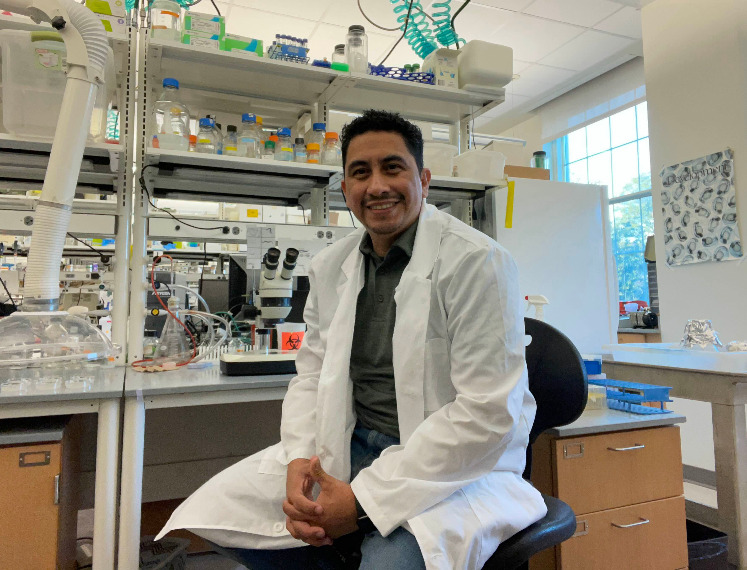 Manuel Ruiz sits in a lab surrounded by equipment.