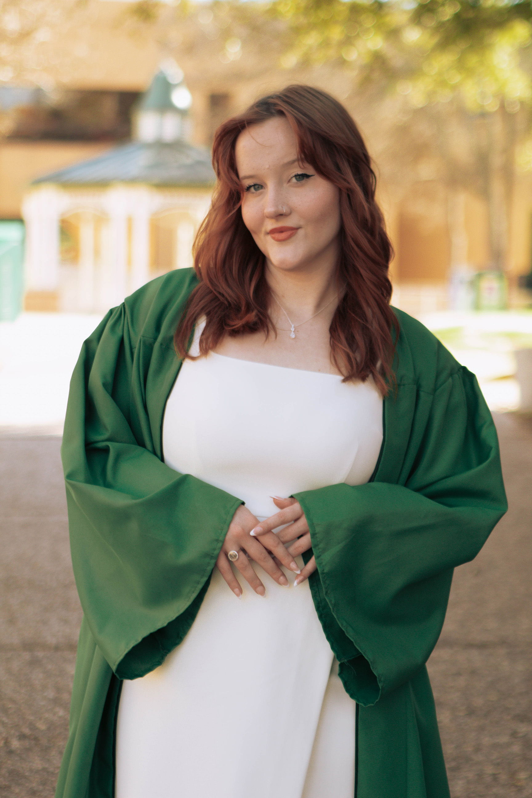 Abigail poses in a green commencement gown