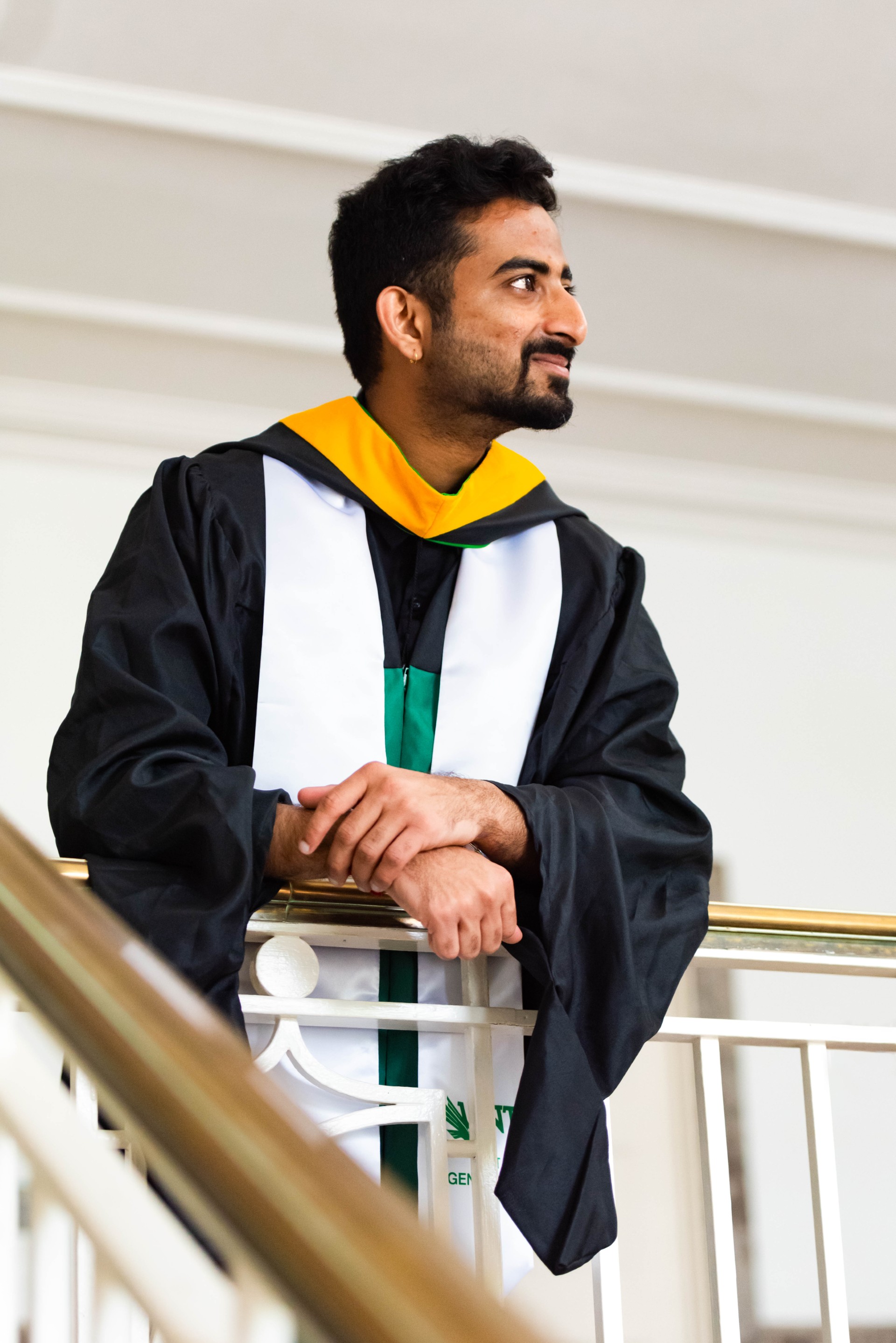 Dheeraj poses in commencement regalia on a balcony.