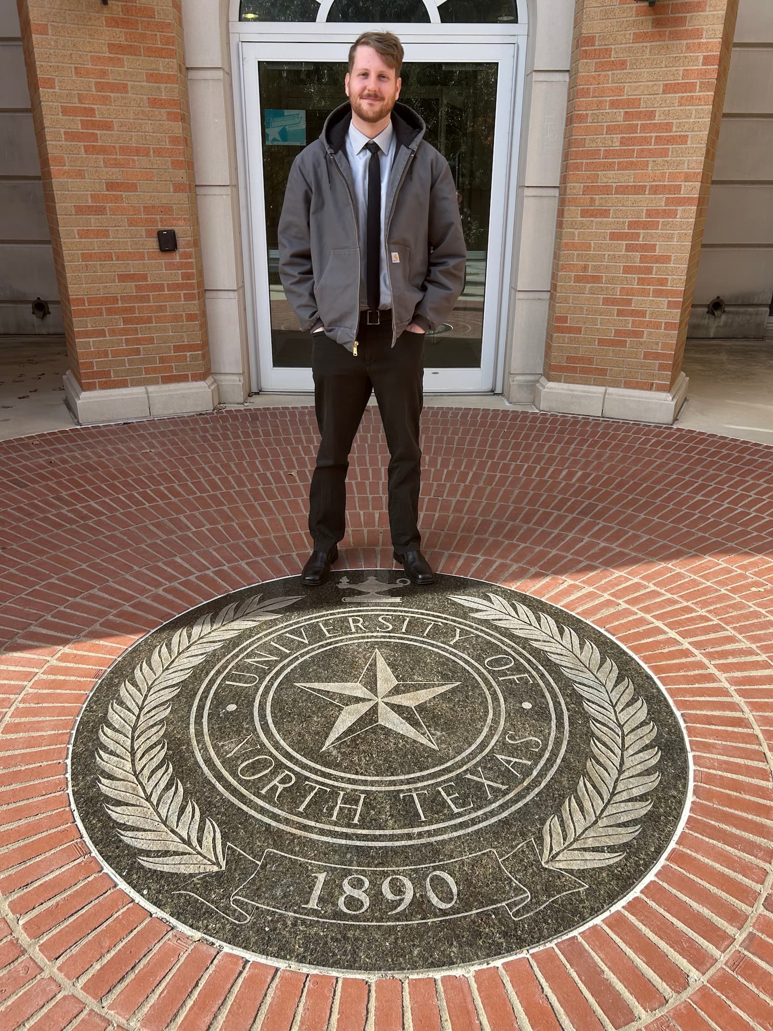 Payton Whitehead stands behind the university seal