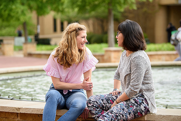 Students talking to each other at a fountain on UNT campus. 