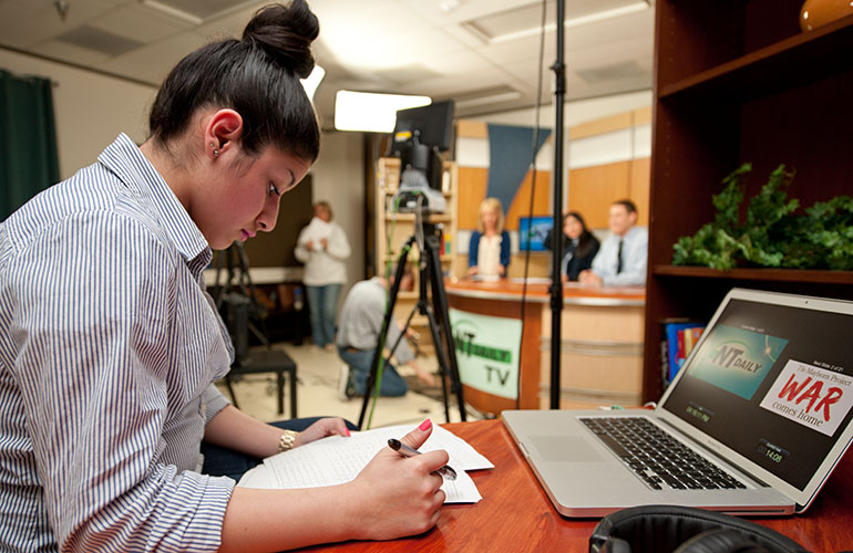 Broadcast student studying a script in the television studio.