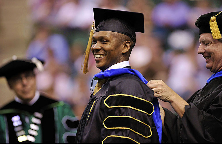 Smiling UNT graduate at hooding ceremony