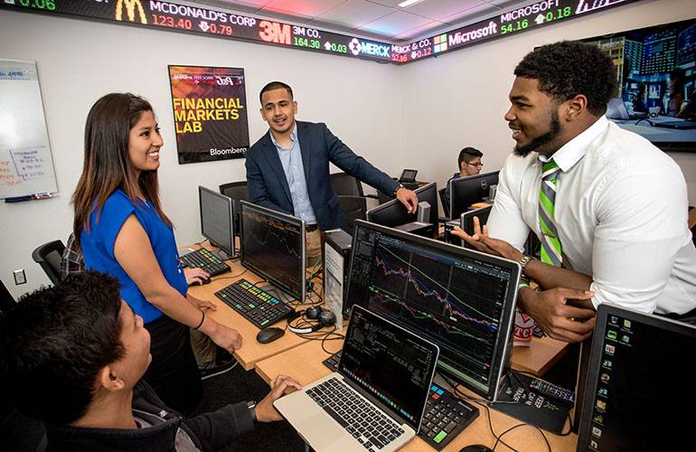 Business students having a conversation in the stock ticker room at the Business Leadership Building.