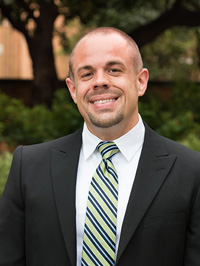 Man wearing a suit with a striped tie smiling. 