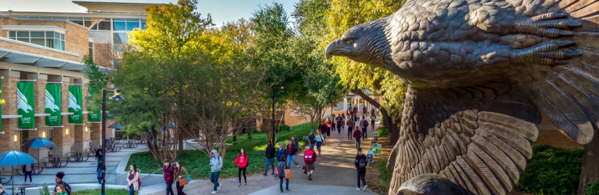 Students walking on campus near the Student Union with bronze flying eagle statue in the foreground