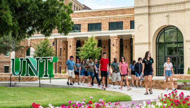 Students walking by large UNT sign