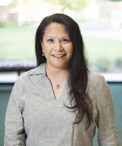 Woman wearing a green blouse smiling. 