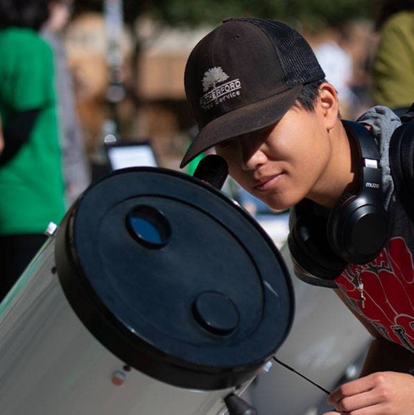 Student looking into a large telescope.