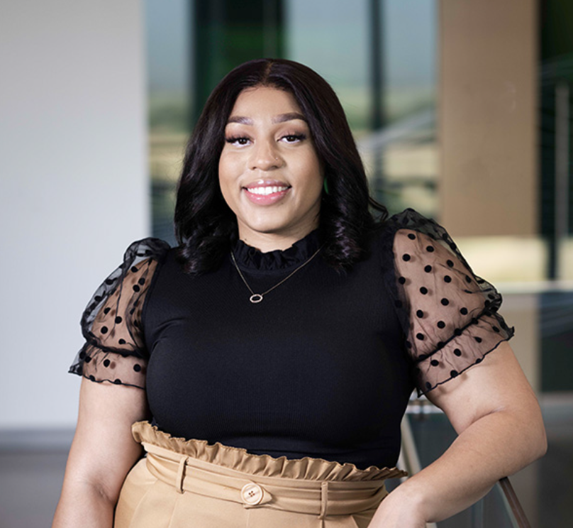 woman wearing a black ruffle blouse with and is smiling