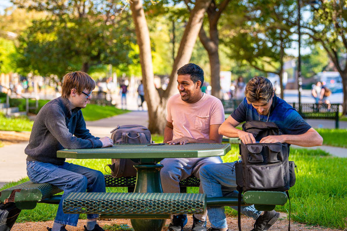 Students talking and laughing together at a picnic table